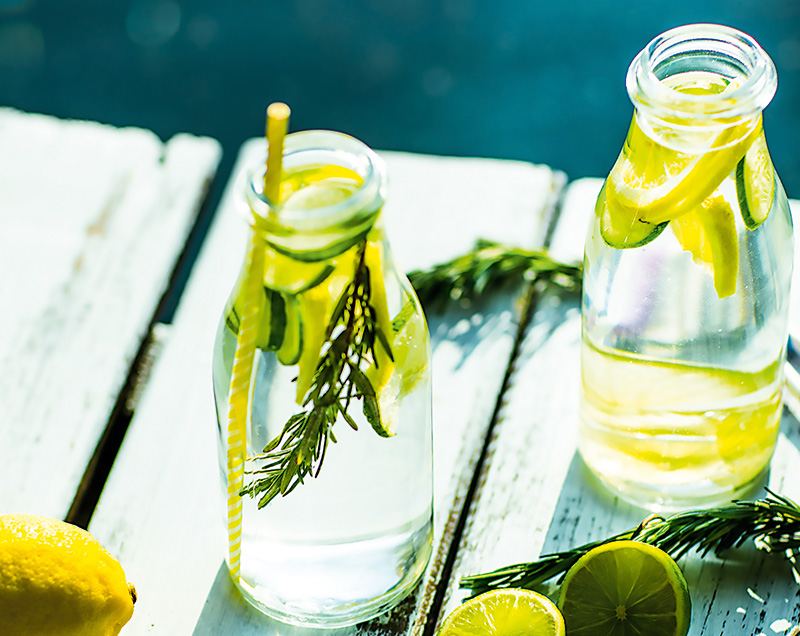 Två flaskor kranvatten med citron- och limeskivor står på en brygga.